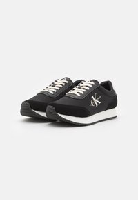 Zapatillas negras con una mezcla de tejido y piel de ante, que presentan cordones blancos, una suela ligera y un pequeño logo en el lateral. Diseño atlético clásico.