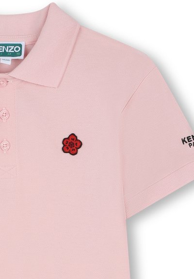Polo rose avec une finition texturée, ornée d'une fleur brodée rouge et noire sur la poitrine et du logo "KENZO" sur la manche.