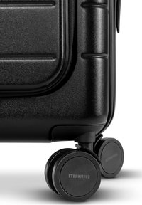 Hartschalenkoffer in Schwarz mit strukturiertem Finish, ausgestattet mit zwei runden Rädern und einem auffälligen Markenlogo auf jedem Rad.