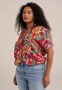 Kurzärmliges, bordeauxfarbenes Blusenshirt mit großen gelben und roten Blumen sowie grünen Blättern. Weiches Material und lockere Passform. Mit Knopfleiste.