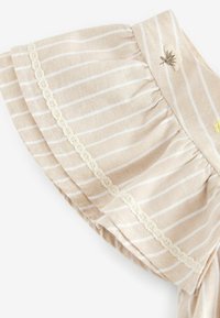 Beige und weiß gestreifter Stoff mit gerafften Kanten, Spitzenbesatz und kleinen bestickten Blumendetails auf leichtem Material.