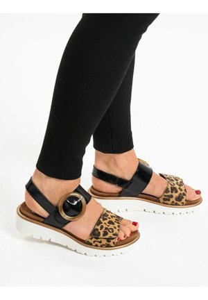 Sandały w leopardzi wzór z czarnym lakierowanym paskiem, dużą okrągłą klamrą i masywną białą podeszwą.