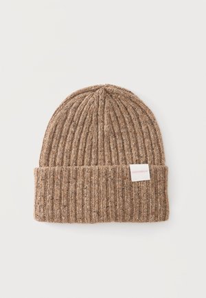 Bonnet en maille côtelée marron avec revers plié et petite étiquette blanche indiquant Coccinelle sur fond clair.