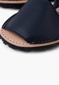 Sandalo in pelle blu navy con design open toe, caratterizzato da cuciture crema e suola in gomma nera testurizzata.