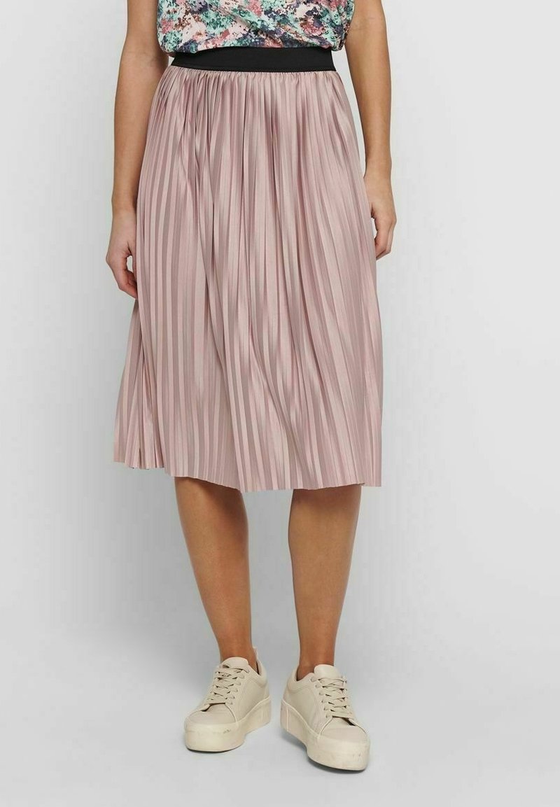 Plissé midi-rok in zachtroze stof met een zwarte elastische tailleband. Draagt bij lichte beige sneakers. Soepele textuur, vloeiend ontwerp.