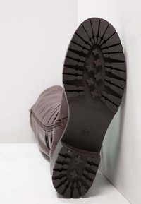 Bota de cuero marrón con una suela texturizada que presenta profundos relieves. Incluye una cremallera lateral para facilitar el calzado. Talla marcada 37.