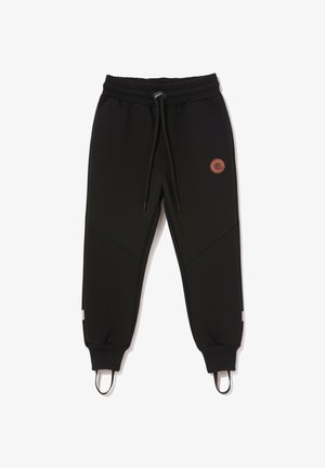 Czarne spodnie dresowe dla dzieci z elastycznym paskiem w talii, sznurkiem do regulacji, prążkowanymi ściągaczami, paskami na stopy oraz małym, okrągłym pomarańczowym logo na prawej części uda.