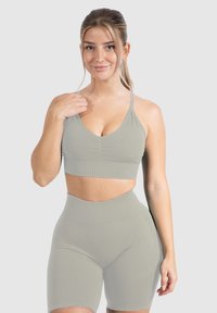 Conjunto de sujetador deportivo gris claro y pantalones cortos de cintura alta, hecho de una tela suave y elástica con un diseño ajustado y una sutil textura acanalada.