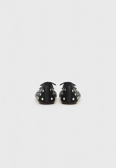 Chaussures plates noires à pois blancs, bout arrondi, lacets en tissu et surface lisse. Comprend des œillets décoratifs et une semelle douce.