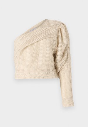 Cream textured crop jacket with a diagonal neckline, puffed sleeve, and woven leaf pattern, featuring a ribbed hem.