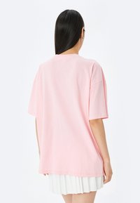 Lyserød bomulds-T-shirt med korte ærmer, løs pasform, rund halsudskæring og en glat tekstur. Har et ensfarvet design uden mønstre eller accenter.