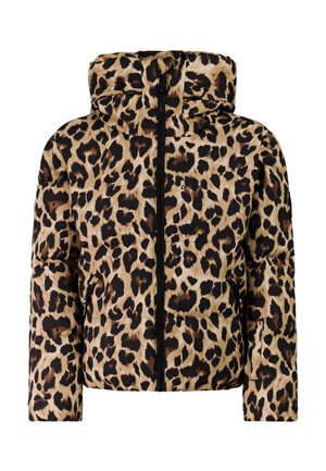 Persoon die een jas met luipaardprint, zwarte broek, zwarte muts, oranje zonnebril en zwarte snowboots draagt, staand met handen in de zakken.