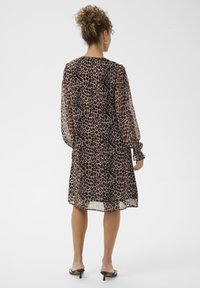 Rochie transparentă, cu imprimeu leopard, cu mâneci lungi tip balon, accente negre, de lungime până la jumătatea coapsei și o croială lejeră. Detaliată cu un decolteu rotund.