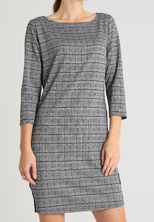 Robe à carreaux gris et noir avec des manches trois-quarts, un décolleté carré et une silhouette ajustée, réalisée dans un tissu texturé.