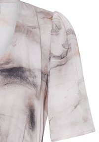 Blouse de couleur claire avec des motifs abstraits gris et beige semblables à du marbre et des manches légèrement bouffantes jusqu'au coude.