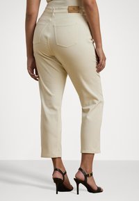 Beige denimbukser med slim fit og cropped længde, der har høj talje, baglommer og et lædermærke på taljen.