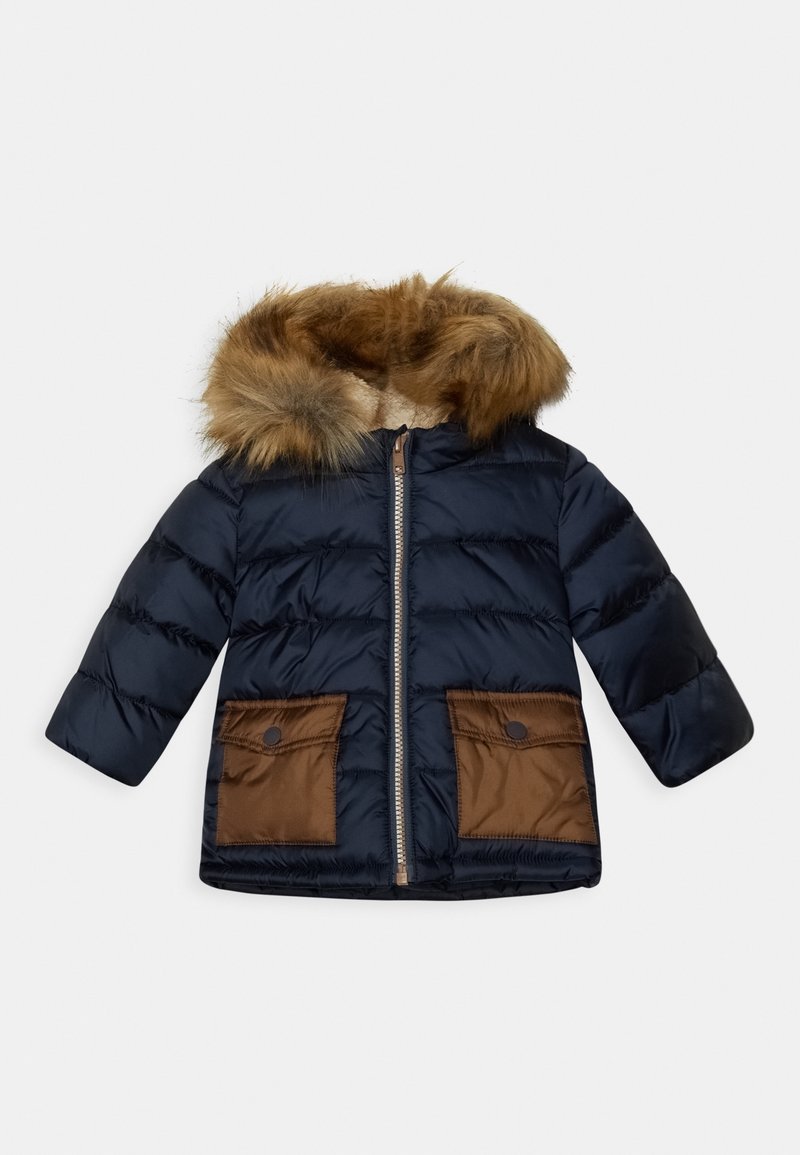 Chaqueta acolchada navy con capucha forrada de piel sintética, que presenta bolsillos de tela marrón y un cierre de cremallera. Hecha de material brillante y acolchado.