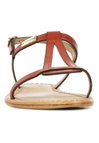 Bruine leren sandaal met een gepolsterde zool, voorzien van meerdere slanke banden en een gespsluiting. Textuurafwerking en minimalistisch ontwerp.