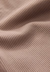 Ljusbrunt ribbat tyg med en mjuk textur. Närbilden visar fina vertikala linjer och diskret glans, som framhäver dess stretch och mjukhet.