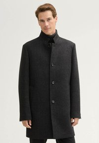 Cappotto di lana grigio scuro con colletto rialzato, sei bottoni, tasche laterali e una linea dritta per un aspetto sartoriale.
