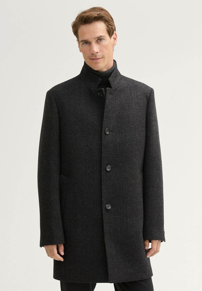 Cappotto di lana grigio scuro con colletto rialzato, sei bottoni, tasche laterali e una linea dritta per un aspetto sartoriale.