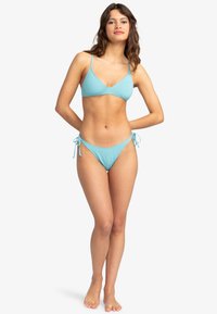 Ljusblå bikini med en tredelad topp med tunna band och justerbara sidband, tillverkad av mjukt tyg.