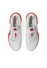 Hvide sportssko med røde detaljer, mesh-overdel, tekstureret design og flade snørebånd. Brandlogo synligt på tungen og siden.