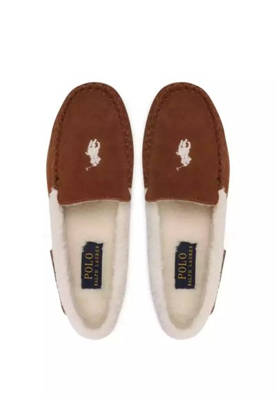 Hnědé semišové pantofle s bílým chlupatým lemováním, zdobené malým bílým vyšitým logem a tmavě modrou štítkem s nápisem "POLO RALPH LAUREN".
