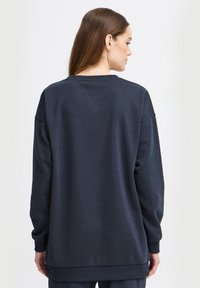Mørkeblå oversized sweatshirt med ribbede manchetter og kant. Blødt, struktureret stof med rund halsudskæring og sænkede skuldre. Minimalistisk design.
