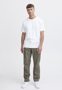 Tricou alb din bumbac, pantaloni cargo olive cu buzunare laterale și adidași albi. Croi slim și design casual cu o textură simplă.