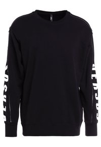 Le sweat-shirt noir présente un col ras du cou, des manches longues avec des fermetures éclair, et un texte imprimé blanc le long des manches. Texture de tissu lisse.