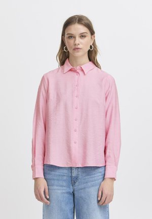 Pink long-sleeve shirt with a button-down front, collar, and a relaxed fit, made from textured fabric; paired with light blue jeans.