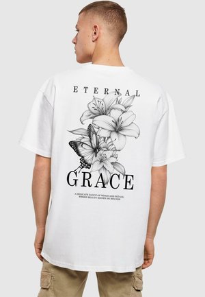 White cotton t-shirt featuring a black floral graphic with a butterfly, text reading "ETERNAL GRACE," and a soft, relaxed fit design.