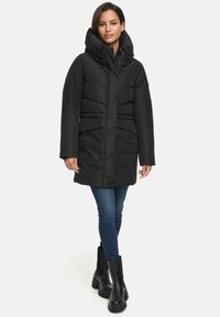 Black padded coat with a high collar, horizontal quilted design, front pockets, and a fitted silhouette. Model wears dark jeans and black boots.