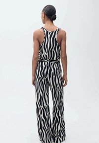 Zwart-witte zebra-gestreepte mouwloze top en wijde broek, met een relaxte pasvorm en een soepele stoftextuur.
