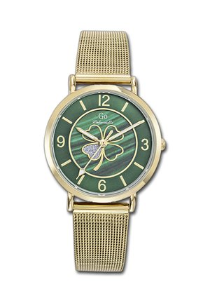 Montre-bracelet à bracelet en maille dorée avec cadran vert, chiffres dorés et un motif de trèfle à quatre feuilles avec une feuille scintillante.