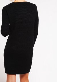 Abito nero lavorato a maglia con motivo a spina di pesce, maniche lunghe e scollatura rotonda, caratterizzato da una silhouette aderente e una texture morbida.