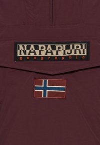 Bordeaux buitenkleding met een groot zwart en beige merklogo en een rood, blauw en witte vlagpatch, wat wijst op Noorse ontwerp.