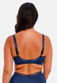 Navy blue bra dengan kain halus, tali yang dapat disesuaikan, dan penutupan kait dan mata. Memiliki jahitan halus dan desain tanpa jahitan.