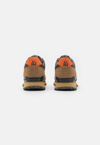 Sneaker marrone e arancione con un design testurizzato, colletto alla caviglia imbottito e suola in gomma con modelli di trazione. Logo sul tallone.