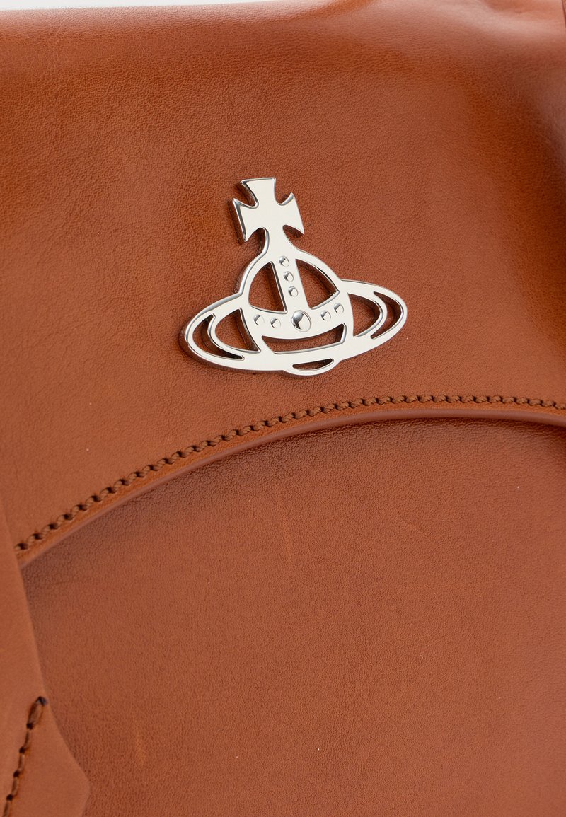 Sac en cuir marron avec un design de logo argenté comprenant des éléments croisés et circulaires. Texture lisse avec des détails de couture visibles.