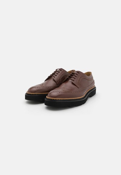 Brune læder dress sko med brogue detaljer, rund tå, snørelukning og en kontrasterende sort gummisål.