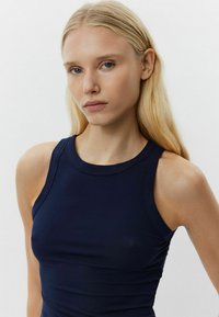 Tengerészkék bordázott ujjatlan top, kerek nyakkivágással. Anyaga sima tapintású és testhez simuló fazonú, mely kiemeli a test kontúrjait.