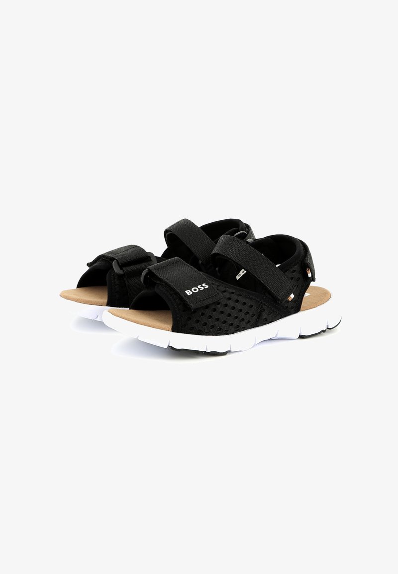 Sandales en mesh noir avec deux brides en Velcro ajustables, upper texturé, semelle intérieure rembourrée et semelle en caoutchouc blanc avec motif d'adhérence.