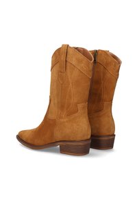 Botas de vaquero de ante marrón con costuras decorativas, punta afilada y tacón apilado de altura media; cierre con cremallera en la parte posterior.