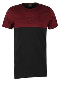 Kortärmad T-shirt med ett röd-mönstrat övre och en enfärgad svart nedre del. Tillverkad av mjukt tyg, med geometriska mönster på bröstet.