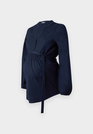 Marineblaue Umstandbluse aus weichem Stoff, mit langen Ärmeln, tiefem Ausschnitt, gerafftem Bund und einem Kordelzug-Detail.