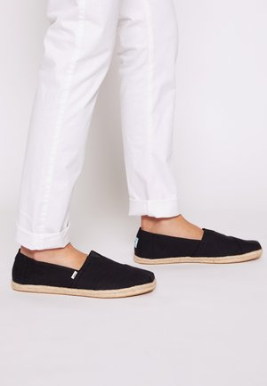 Czarne espadryle na płótnie z paskiem ze sznurka jutowego. Model ma wsuwaną konstrukcję, płaską podeszwę i elastyczne wstawki ułatwiające zakładanie.