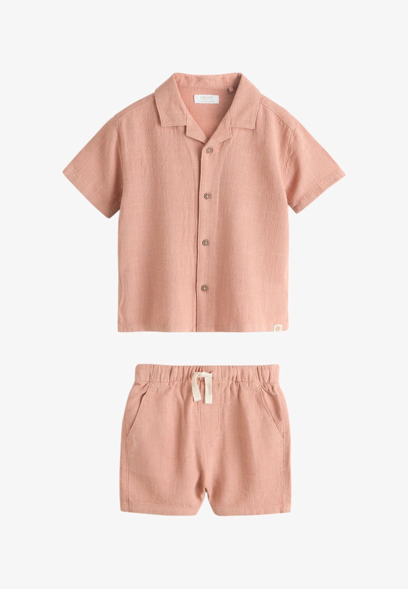Chemise rose poudré à manches courtes avec boutons et short assorti à taille élastique avec cordon blanc, en tissu texturé.
