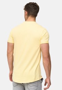Ensfarvet gul t-shirt lavet af bomuld med korte ærmer, en klassisk rund halsudskæring og en lige kant. Blød struktur, set bagfra.